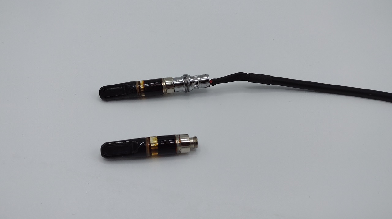 510-threaded power cable connected directly to a bare vape cartridge, beside an unconnected cartridge — the UVM drives cartridges directly, bypassing consumer batteries