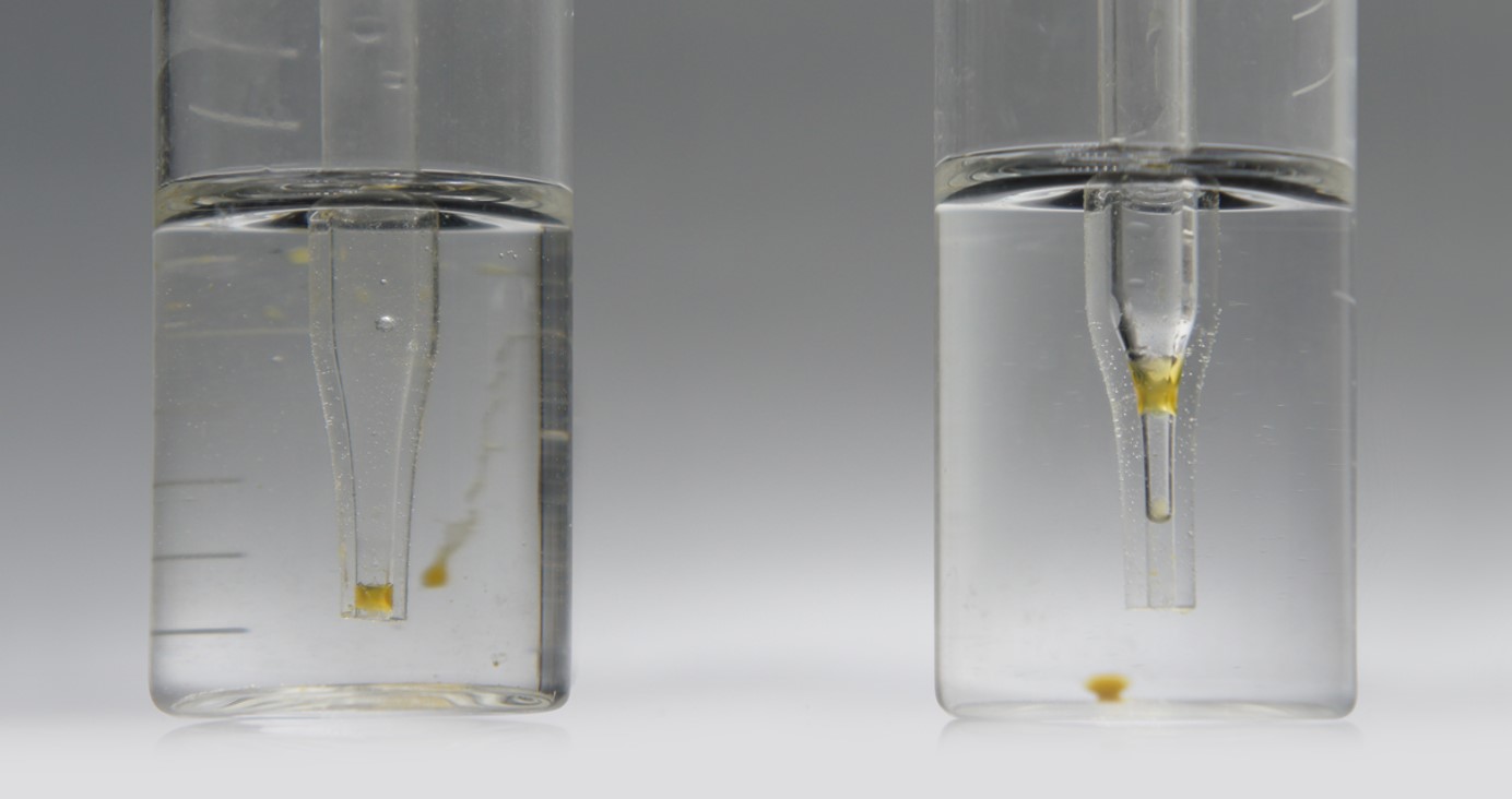 Two glass impingers showing yellow aerosol precipitate captured from vapor — the sticky condensate that fouls non-disposable flow paths